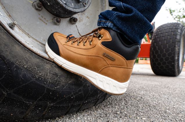 Brown lwork composite toe boot with white sole on a tire, likely used for work or outdoor activities.